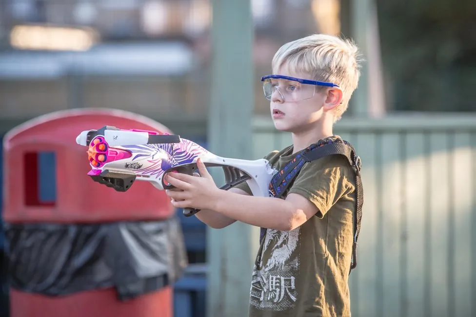 A child aiming a NERF blaster at a NERF gun party