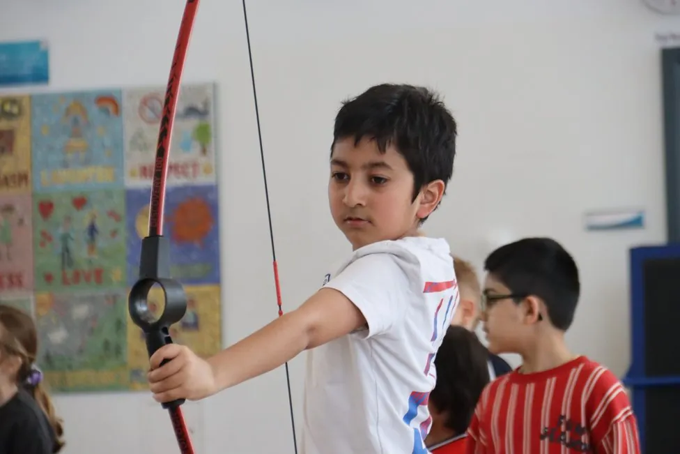 A child drawing a bow at a soft archery session